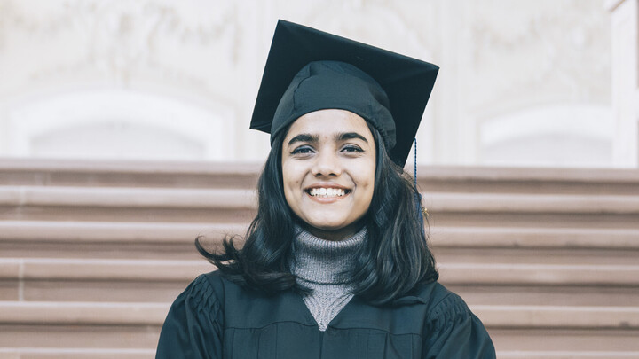 Kriti Bhattacharya. She has long brown hair and is wearing a black gown.