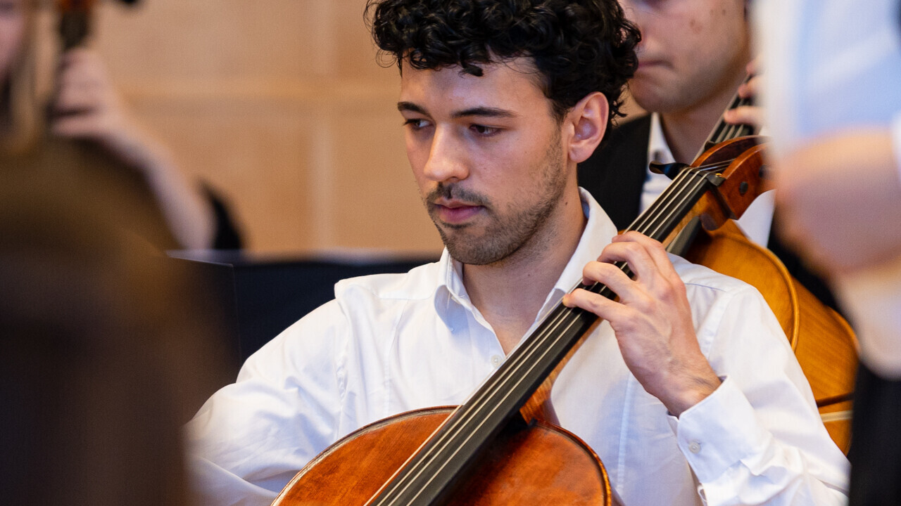 Auftritt des Uniorchesters. Student spielt ein großes Streichinstrument.