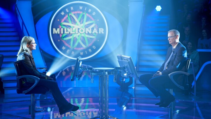 Sophia Rishyna sitzt in einer Quizshow. Das Set ist blau ausgeleuchtet. Ihr gegenüber sitzt der Showmaster Günther Jauch. Im Hintergrund ist ein großes Schild zu sehen, auf dem "Wer wird Millionär" steht.