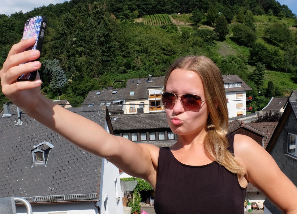 Eine Frau macht ein Selfie auf der Dachterasse.