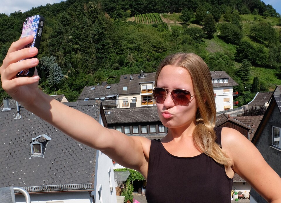 Eine Frau macht ein Selfie auf der Dachterasse.