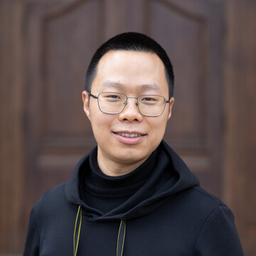 Portrait of Siyu Zhang. He is wearing a black sweater and standing in front of a door of Mannheim Castle.