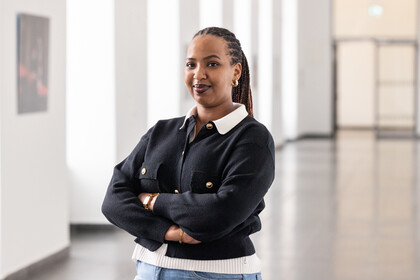 Portrait von Aurore Zoé Ikirezi Akuzweyezu. Sie trägt eine weiße Bluse und eine schwarze Jacke mit goldenen Knöpfen.