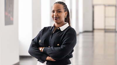 Portrait von Aurore Zoé Ikirezi Akuzweyezu. Sie trägt eine weiße Bluse und eine schwarze Jacke mit goldenen Knöpfen.