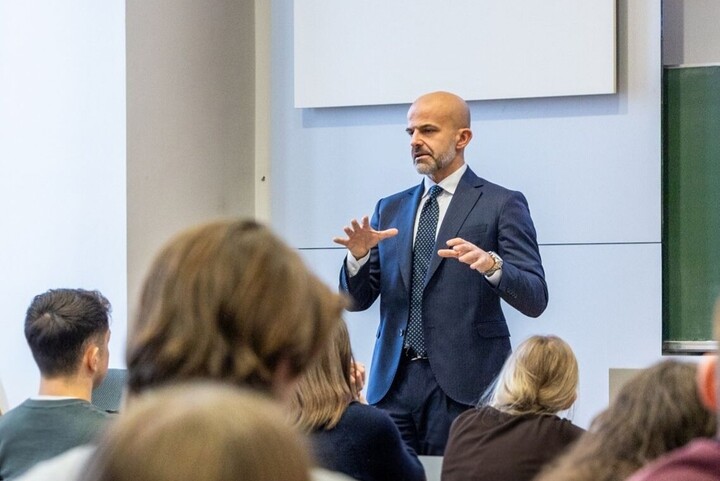 Foto in gut besuchtem Hörsaal mit Blick auf Vortragenden
