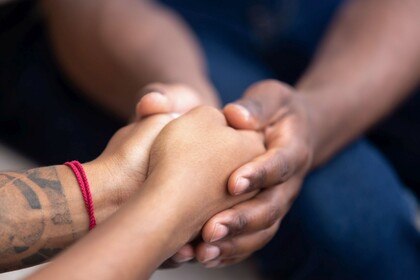 Die gefalteten Hände einer Person werden von den Händen einer zweiten Person umschlossen