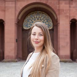 Anna Wildhirt hat langes, blondes Haar. Sie trägt eine beige Jacke und darunter eine weiße Bluse.