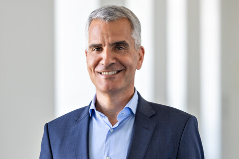 Prof. Dr. Thomas Fetzer trägt ein dunkelsblaues Sakko und ein hellblaues Hemd. Er hat kurzes graues Haar und lächelt. 