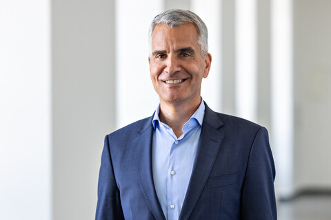 Prof. Dr. Thomas Fetzer trägt ein dunkelsblaues Sakko und ein hellblaues Hemd. Er hat kurzes graues Haar und lächelt.
