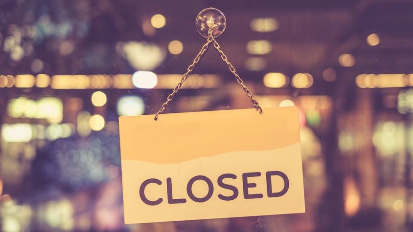 An einr Türe hängt ein Schild mit der Aufschrift "Closed".