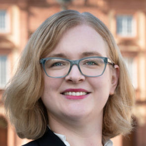 Prof. Rhese has shoulder-length blond hair and wears glasses.