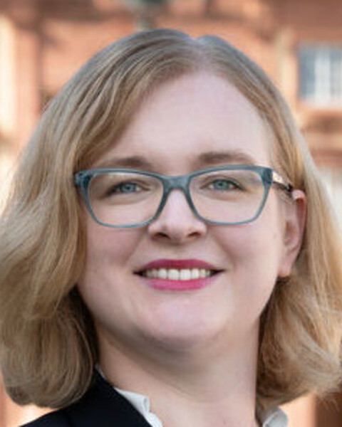 Prof. Rhese hat schulterlange blonde Haare und trägt eine Brille.