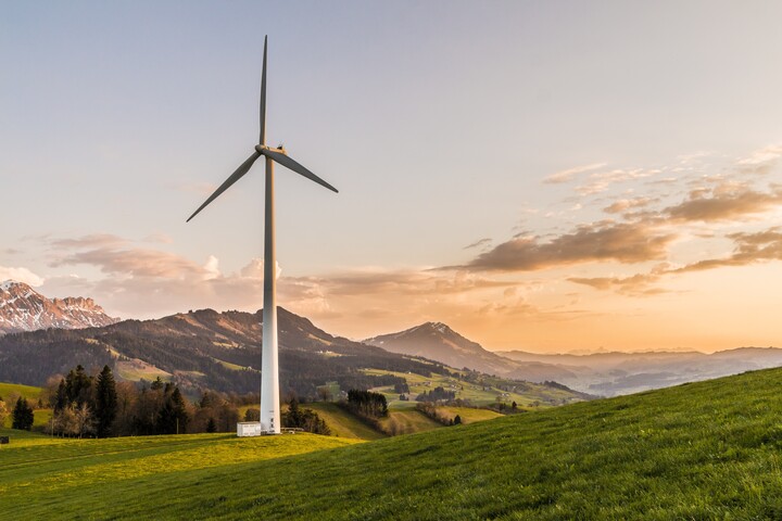Ein Windrad steht in einem hügeligen Gebiet im Sonnenuntergang