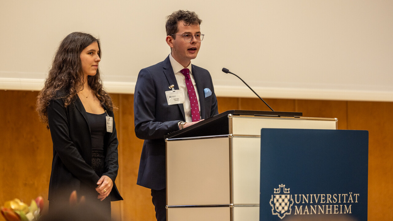 Zwei Personen stehen an einem Rednerpult und sprechen