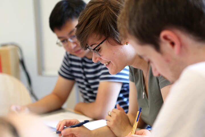 Three students sit next to each other and study.