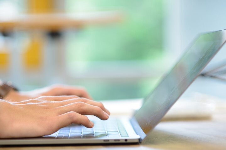 Eine Person tippt auf einem silbernen Laptop.