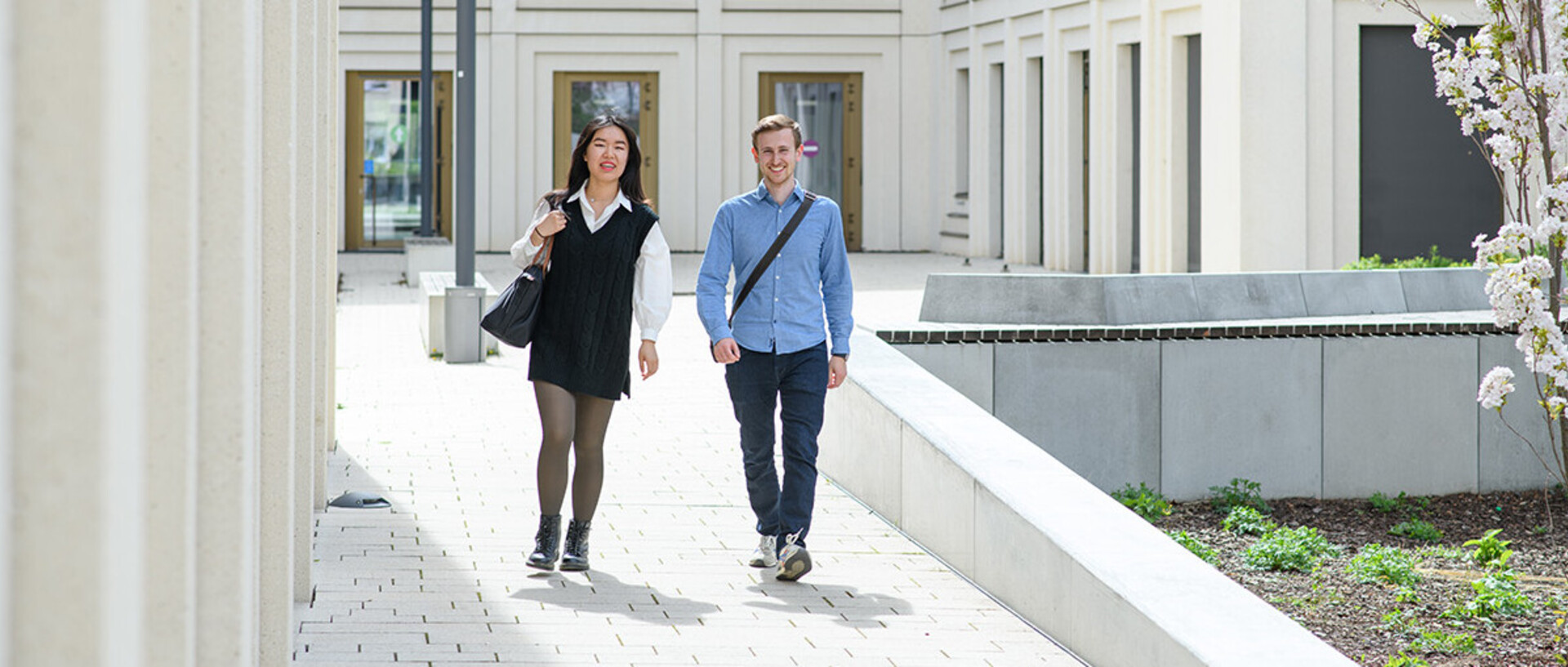 Two doctoral students are walking out of the courtyard of the B6 building.