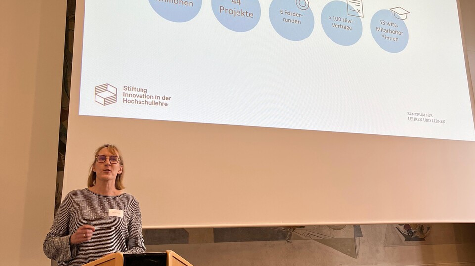 Person am Rednerpult bei der InnoMA-Abschlussveranstaltung mit Präsentationsfolie im Hintergrund.