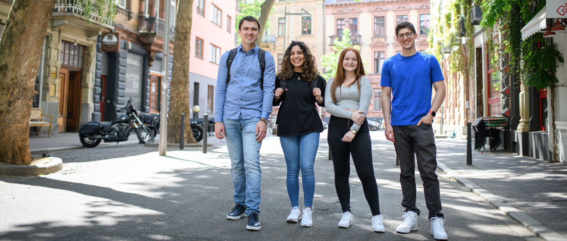 Four smiling students in a low-traffic zone in Mannheim’s Jungbusch district