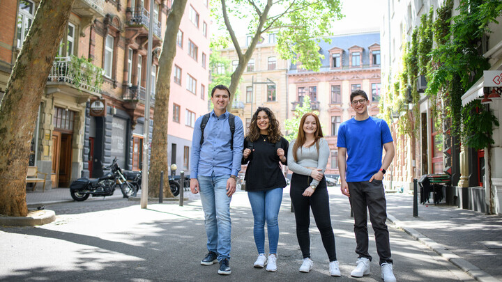 Four smiling students in a low-traffic zone in Mannheim’s Jungbusch district