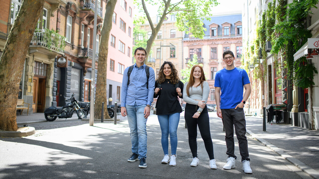 Four smiling students in a low-traffic zone in Mannheim’s Jungbusch district