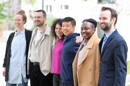 Six people are standing in a row. They have different genders and cultural backgrounds. 