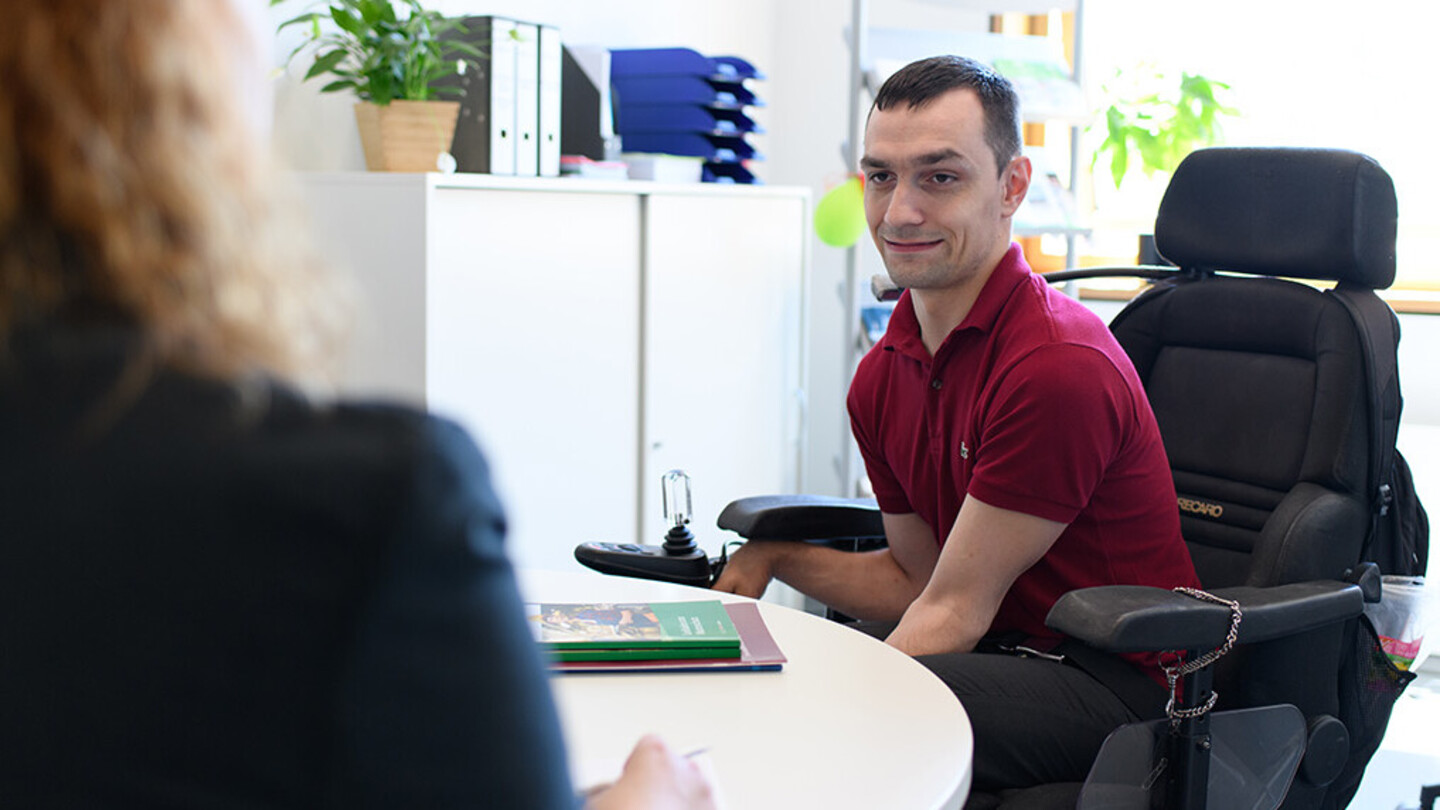 An employee advises a student who is in a wheelchair.