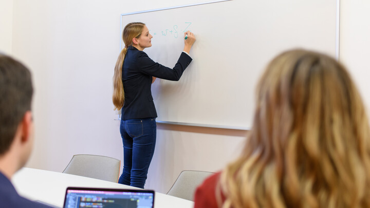 A person writing something on a whiteboard