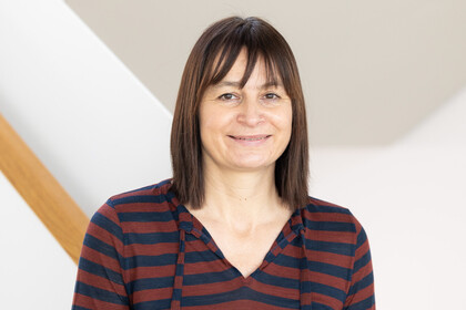 Carola Trips vor einem hellen Hintergrund. Sie trägt ein gestreiftes Kapuzenoberteil.