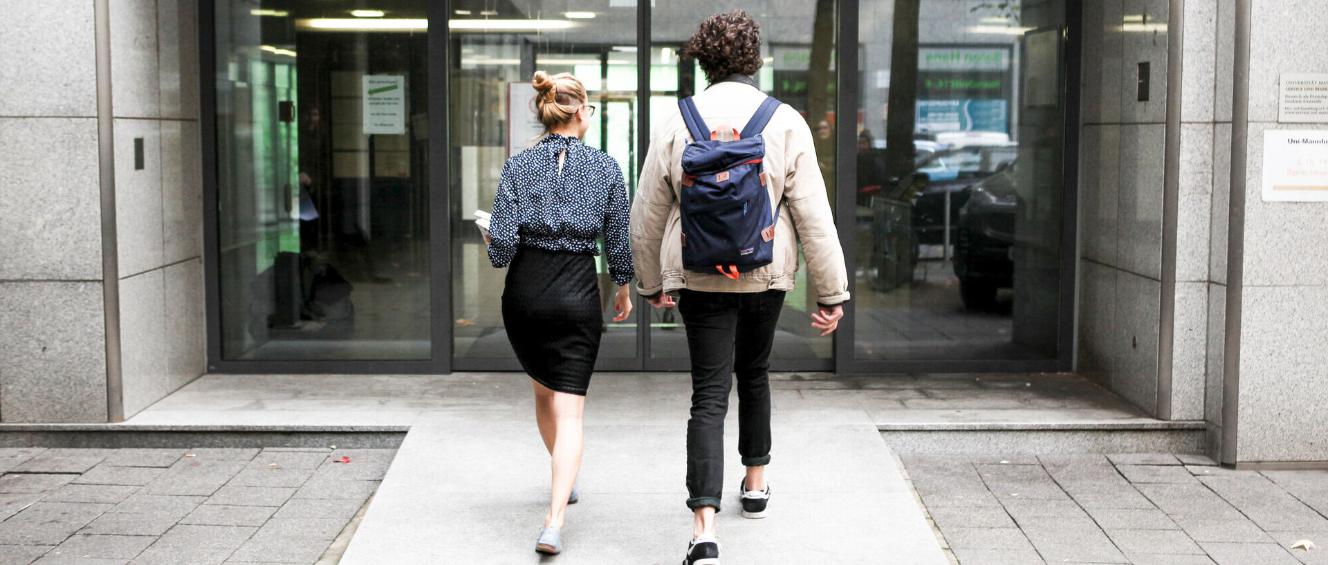 Zwei Studierende betreten das Unigebäude