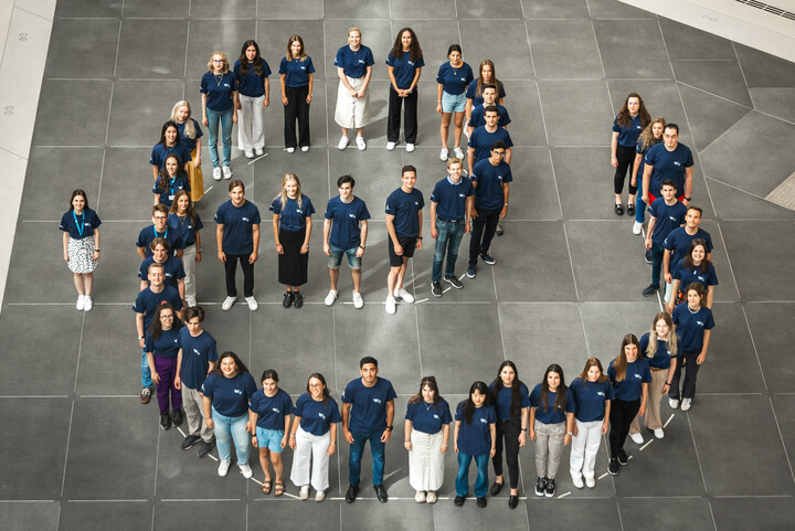 Eine Gruppe von Menschen steht nebeneinander, sodass sie zusammen das Logo von Engage.EU formen. Alle tragen einn dunkelblaues T-Shirt. 