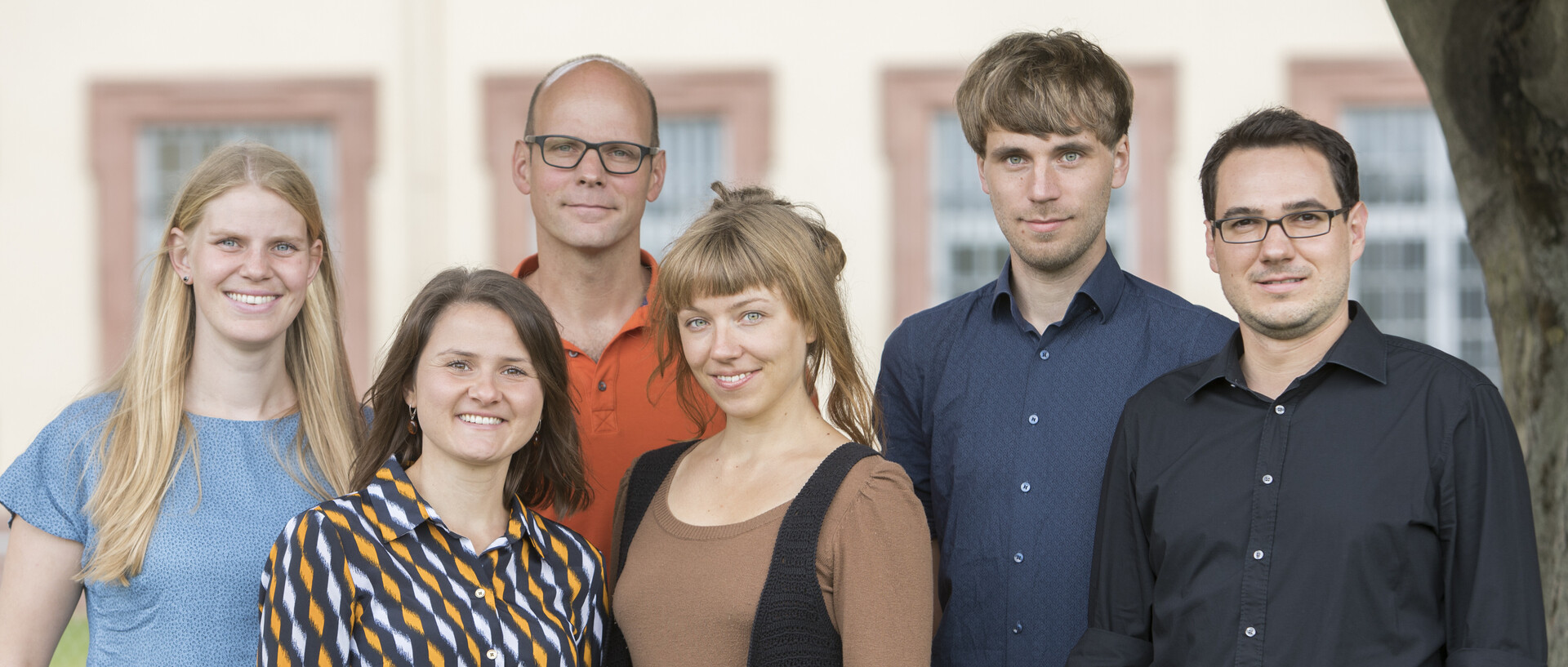 Sechs Personen stehen nebeneinander vor dem Schloss. 