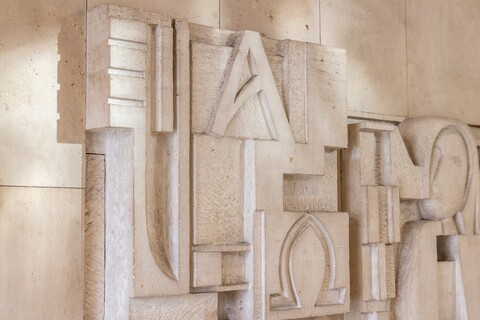 Kunstwerk mit Kopf in einer Steinmauer eingemeißelt