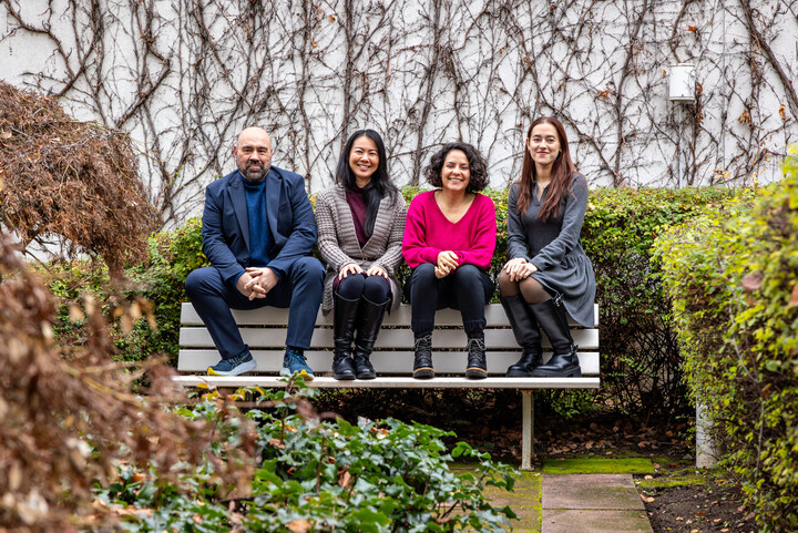 Vier Personen sitzen auf der Lehne einer Bank im Außenbereich des IBZ.