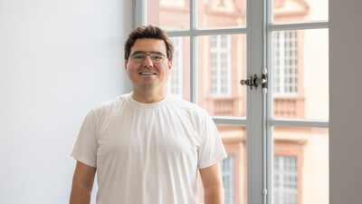 Ayhan trägt ein weißes T-Shirt und eine Brille.