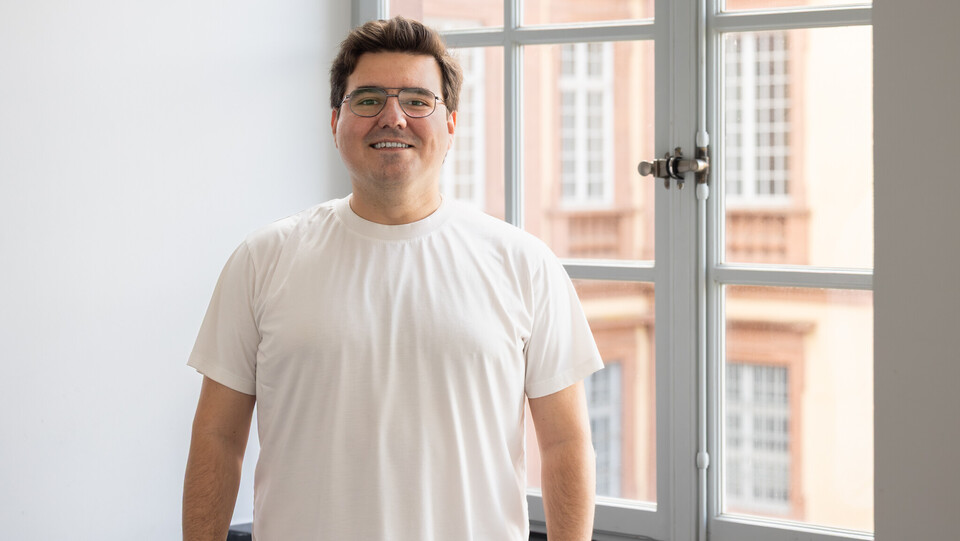 Ayhan trägt ein weißes T-Shirt und eine Brille.