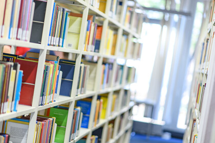 Helle Bibliothekregale mit vielen bunten Büchern. 