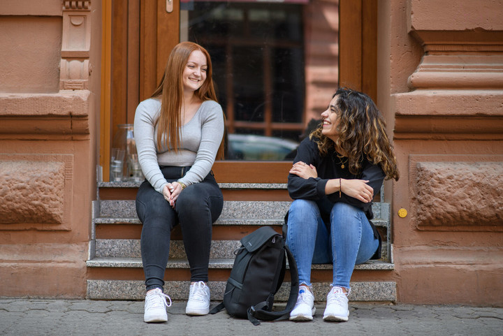 Zwei Studentinnen auf der Steintreppe eines Wohnhauses