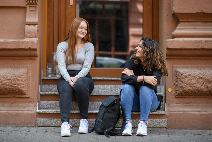 Two students at the stone staircase of a building