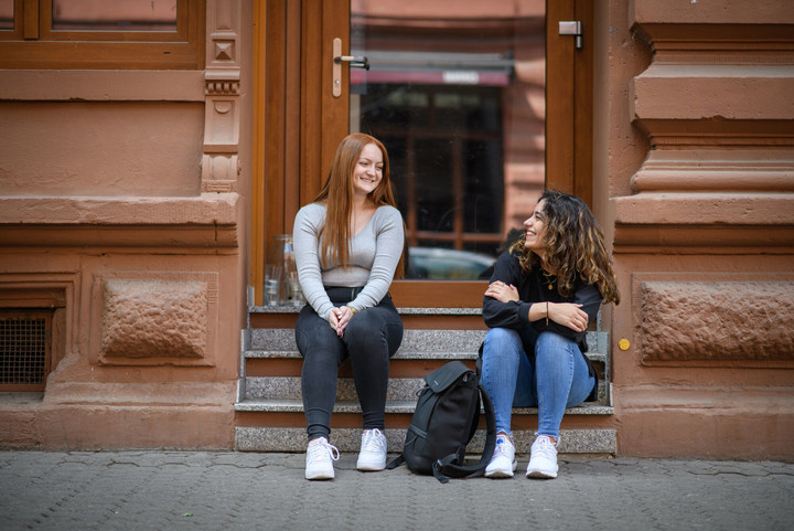 Two students at the stone staircase of a building