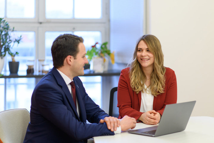 Two people in discussion in front of a laptop