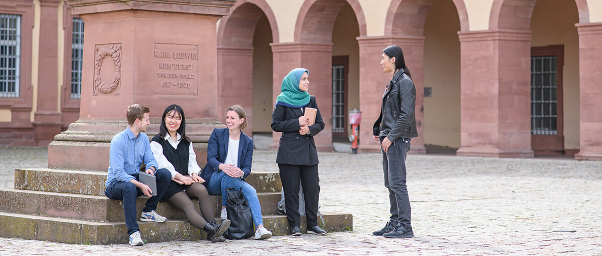 Five students conversing by the statue on the Ehrenhof