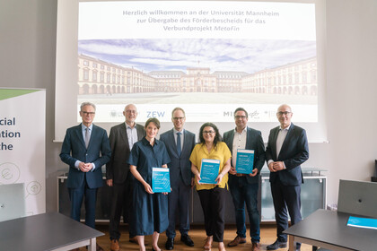 Die Projektleiter des MetaFin-Projekts stehen zusammen mit dem Rektor der Universität, dem Staatssekretär, dem Leiter des ZEW und dem Dekan der BWL-Fakultät im Senatssaal und präsentieren den Förderbescheid.
