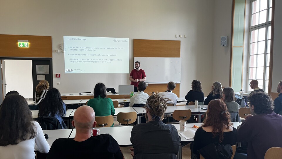 Tobias Rettig steht vor dem Publikum und hält eine Präsentation. Er trägt ein rotes T-Shirt.
