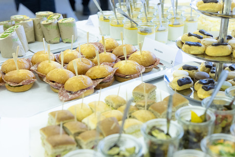 Ein gefüllter Buffet-Tisch mit Mini-Eclairs, Wraps und weiteren Speisen