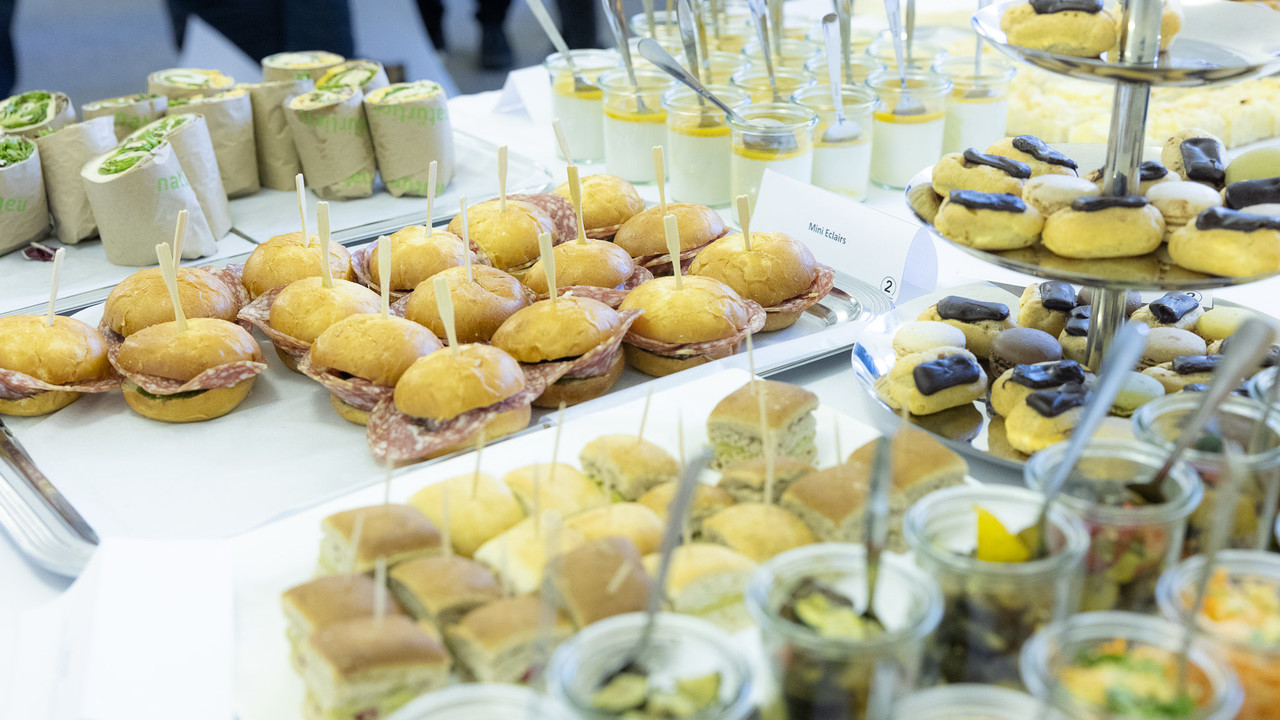 Ein gefüllter Buffet-Tisch mit Mini-Eclairs, Wraps und weiteren Speisen