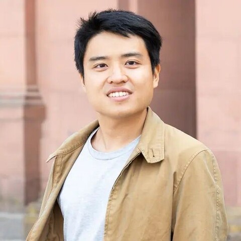 Noel Chia has short black hair. He is wearing a beige jacket and a gray T-shirt.