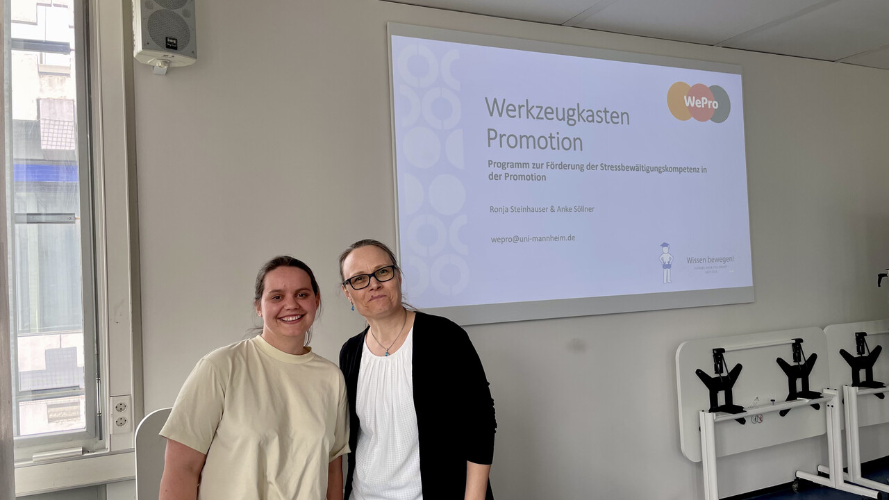 Am 12. Mai 2026 startete das Projekt "Werkzeugkasten Promotion" von Ronja Steinhauser und Dr. Anke Söllner 2 weibliche Personen stehen in einem Seminarraum vor einer Powerpointpräsentation auf dem Beamer zum Thema "Werkzeugkasten Promotion"