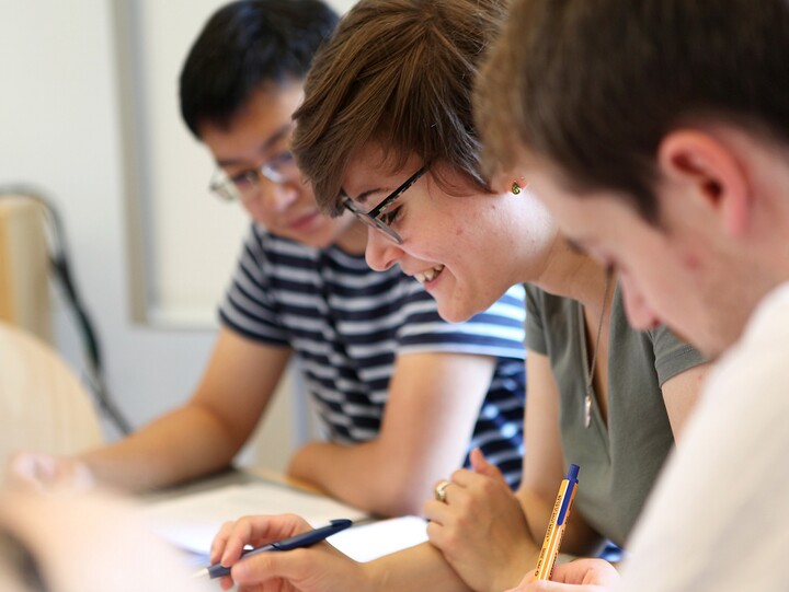 Three students sit next to each other and study.