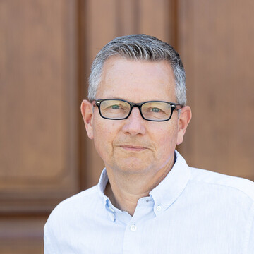 Olaf Raband hat kurze graue Haare. Er trägt eine schmale schwarze Brille und ein weißes Hemd.